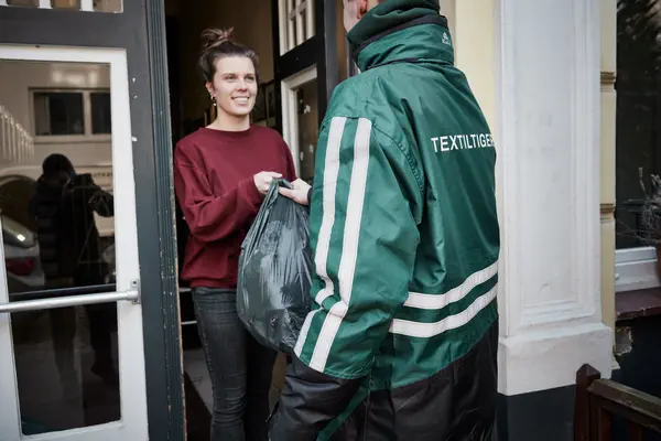 Auf dem Foto holt ein Mitarbeiter von Textiltiger Altkleider bei einer Kundin ab.