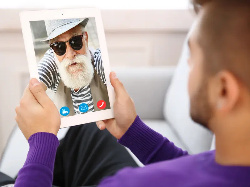 Junger Mann mit Opa im Videochat per Tablet