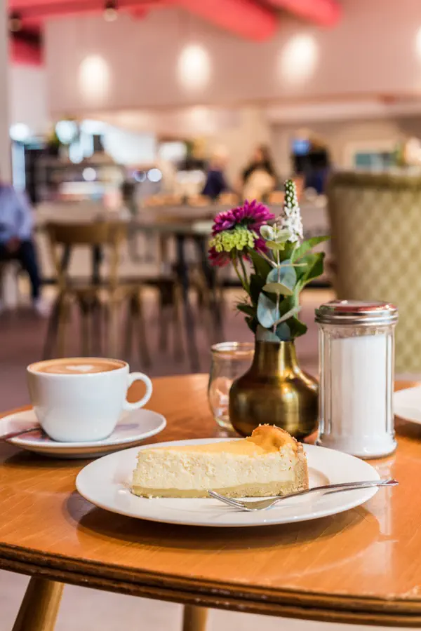 Ein Tisch mit einer Tasse Kaffee und einem Stück Käsekuchen im Café Kuchentratsch.